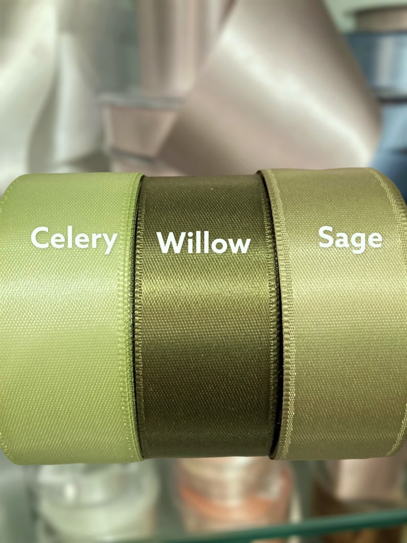 May include: Close-up of three spools of ribbon in shades of green. The colors are labeled "Celery", "Willow", and "Sage". The ribbon has a satin finish and a woven texture, ideal for crafts and gift wrapping.