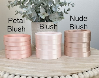 May include: Three spools of satin ribbon in different shades of pink. The spools are labeled "Petal Blush", "Blush", and "Nude Blush".