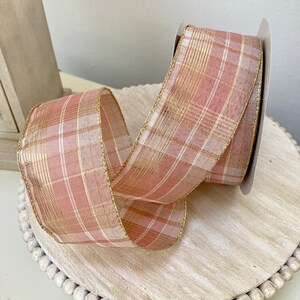 Puede incluir: Cinta de cuadros rosa y dorada con textura transparente. La cinta tiene un hilo metálico dorado tejido en el patrón de cuadros.