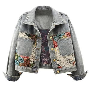 May include: Pale blue denim jacket featuring floral embroidery on the front pockets and panels. The jacket has a classic collar, button fastenings, and cuffed sleeves. The floral design includes red, blue, and green flowers.
