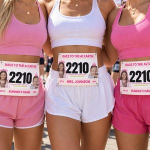 Pode incluir: Três números de peito com a etiqueta Race to the Altar 5K e o número 2210, com pequenas fotos de crianças, um ícone de coroa rosa e o texto Official Race Bib Party. Os números incluem espaços para o nome e a data 22 out 2025.