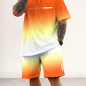 May include: Orange, yellow, and white gradient t-shirt and shorts set. The t-shirt has the word "BALANCE" printed on the chest. The shorts have a matching gradient design. A modern and stylish athletic outfit.