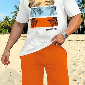 May include: White t-shirt and orange shorts set. The t-shirt features a graphic of palm trees in three horizontal bands of color: yellow, blue, and orange. The text "COCONUT TREE" is printed below the graphic. The shorts are a solid orange color.