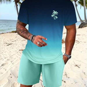 May include: A two-piece matching set featuring a gradient design. The t-shirt transitions from navy blue to turquoise, with a small palm tree graphic. The shorts are turquoise. The set is made of a soft, lightweight material.
