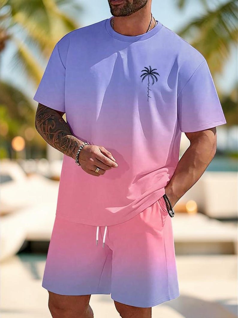 May include: A two-piece outfit featuring a gradient design. The top is a short-sleeved t-shirt with a palm tree graphic and the shorts have a drawstring. The color scheme transitions from purple to pink.