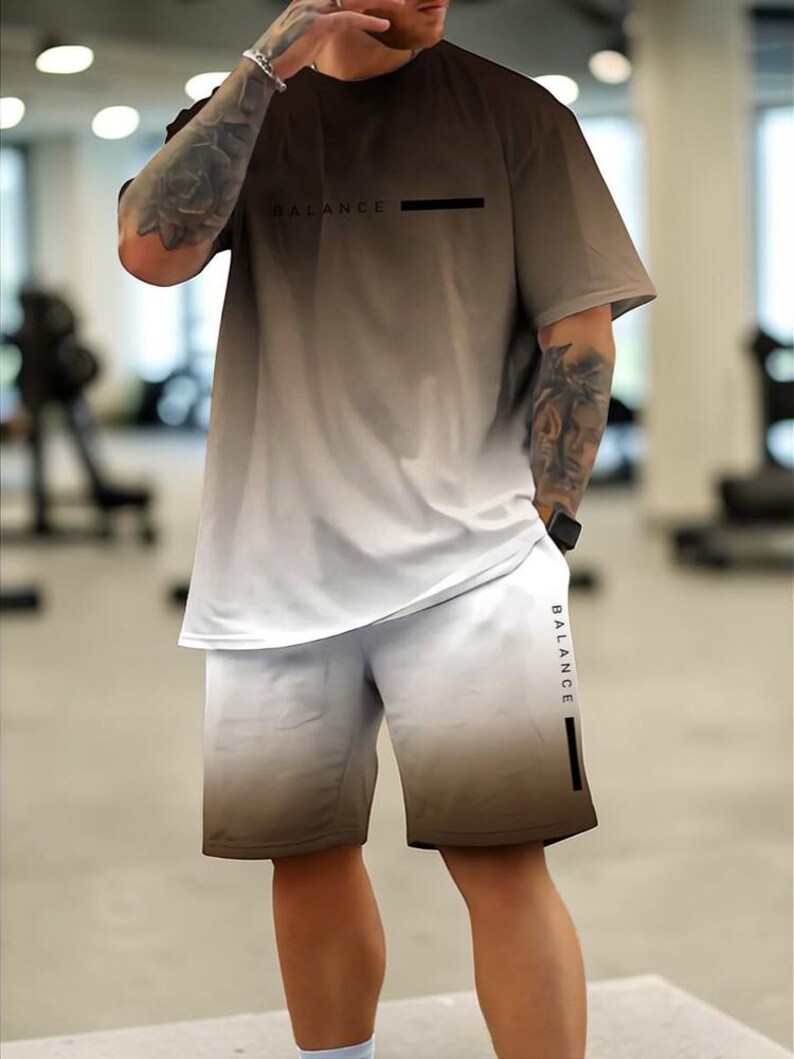 May include: A two-piece athletic set in a brown to white gradient. The short-sleeved top has "BALANCE" printed on the chest. The matching shorts also feature the word "BALANCE" on the side. The set is made of a lightweight, breathable fabric.