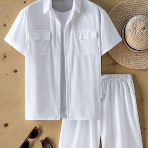 May include: A white short-sleeved shirt and shorts set with two chest pockets. The outfit is paired with a straw hat and two pairs of sunglasses. The clothing is made of a lightweight fabric, perfect for warm weather.