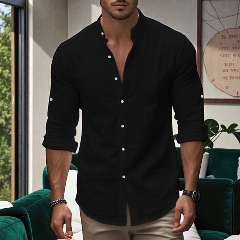 May include: Black long-sleeve shirt with a mandarin collar and white buttons. The shirt has buttoned cuffs and is partially unbuttoned. The shirt is made of a lightweight fabric.