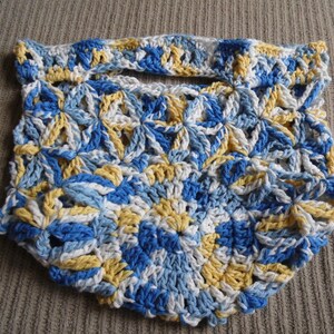May include: Handmade crochet bag in a floral pattern. The bag features a handle and is made with blue, white, and yellow yarn. The bag is a unique accessory for carrying small items.
