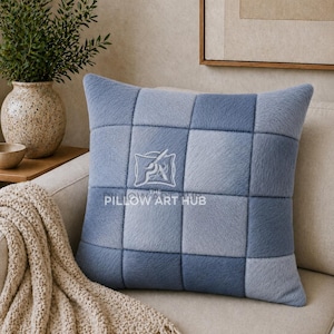 Può includere: Un cuscino quadrato con un design patchwork di quadrati in pelliccia sintetica blu in varie tonalità di blu chiaro e scuro. Il centro del cuscino mostra un logo bianco con il testo THE PILLOW ART HUB e un'icona a forma di pennello stilizzato.