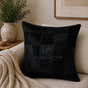 Può includere: Un cuscino quadrato con un design patchwork nero composto da singoli pannelli quadrati. Al centro del cuscino è presente una tenue filigrana con il testo THE PILLOW ART HUB. La consistenza appare simile a quella di una pelle a pelo corto.
