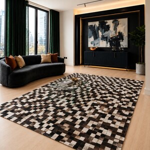 Könnte beinhalten: Ein modernes Wohnzimmer mit einem schwarzen, geschwungenen Sofa, das mit orangefarbenen und beigefarbenen Kissen geschmückt ist. Ein gemusterter Teppich in Braun- und Weißtönen dominiert den Boden. Ein Couchtisch aus Glas steht auf dem Teppich.