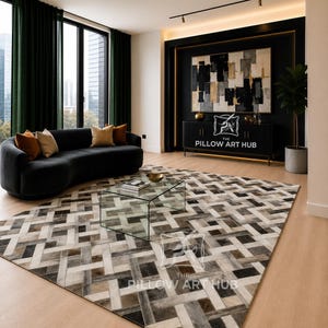 Könnte beinhalten: Ein großer rechteckiger Teppich mit einem geometrischen Webmuster in Grau-, Braun- und Cremetönen. Der Teppich liegt auf einem hellen Holzboden in einem Raum mit einem schwarzen, geschwungenen Sofa, einem Glastisch und einem schwarzen Sideboard.