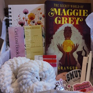 May include: A gift box containing a book, notebook, and other items. The book is titled "The Secret World of Maggie Grey". There is also a white crocheted item, stickers, and a bookmark that says "Get Losi Book".