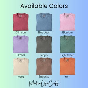 May include: A display of nine folded t-shirts in various colors, including crimson, blue jean, blossom, orchid, pepper, light green, ivory, espresso, and yam. The text "Available Colors" is at the top, with "Made in USA Crafts" at the bottom.