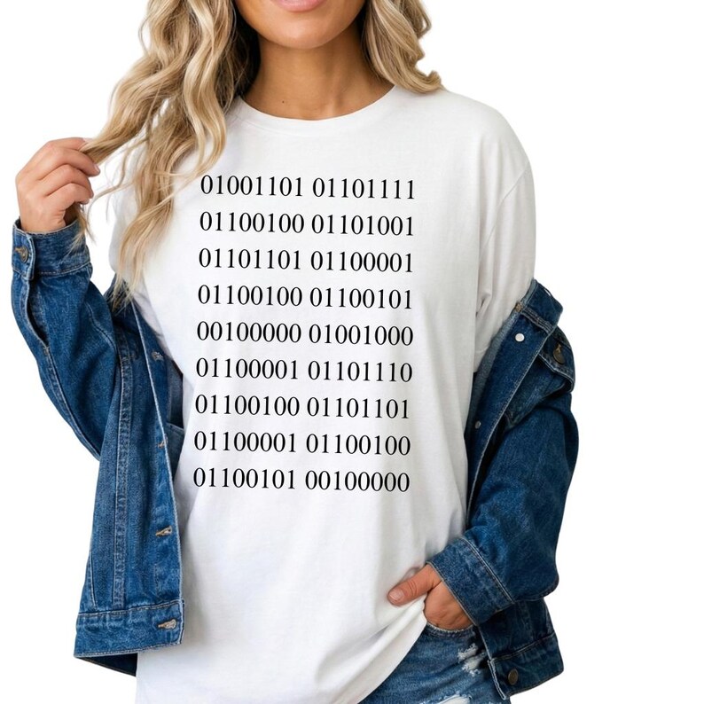 May include: White t-shirt with black binary code text. The text is arranged in rows and columns. The shirt is a casual style, suitable for everyday wear.