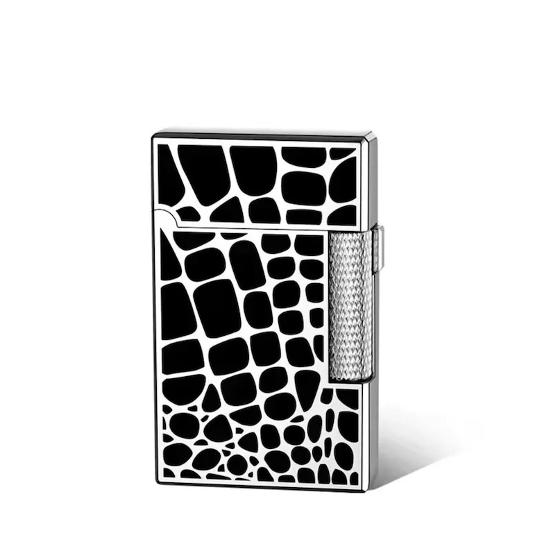 May include: A rectangular lighter with a black and white pattern resembling reptile skin. The lighter has a silver metal body and a textured, silver ignition area.