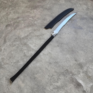 Pode incluir: Uma arma de haste com cabo longo apresentando uma lâmina de aço curva de gume único com um ponto de transição visível na empunhadura. O cabo é envolto em cordão preto e uma bainha de couro preto correspondente com costuras visíveis jaz ao lado.