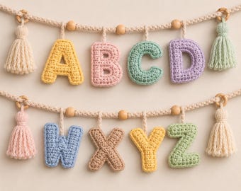 Può includere: Due ghirlande orizzontali con lettere all'uncinetto in colori pastello. La fila superiore mostra A, B, C e D, mentre quella inferiore mostra W, X, Y e Z. Ogni ghirlanda include perline di legno, corda intrecciata e nappe decorative alle estremità.