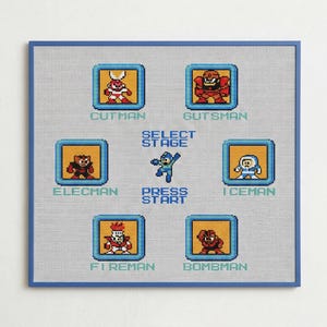 Op de afbeelding: Kruissteekkunstwerk met gepixelde personages uit een klassiek videospel. Het ontwerp bevat personages als Cutman, Gutsman, Elecman, Iceman, Fireman en Bombman, met de tekst "Select Stage" en "Press Start". Het kunstwerk is omlijst door een blauwe rand.