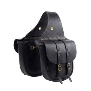 Könnte beinhalten: Eine schwarze Ledersatteltasche mit zwei Taschen, die durch eine Brücke verbunden sind. Jede Tasche hat eine Klappe, die mit zwei vertikalen Riemen und Messingschnallen gesichert ist. Die Kanten sind sichtbar vernäht und die Brücke hat Messingösen.