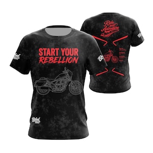Può includere: Una t-shirt nera con motivo grigio screziato che presenta il testo rosso START YOUR REBELLION e un disegno a linee bianche di una motocicletta sul davanti. Il retro mostra il testo rosso Ride your Adventure, una grafica di moto e accenti rossi.