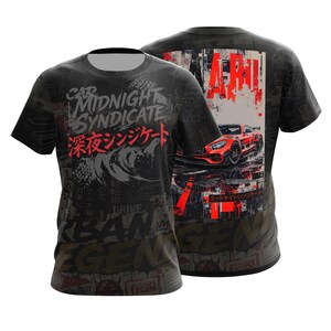 Pode incluir: Uma t-shirt preta de manga curta com uma estampa gráfica que inclui o texto Midnight Syndicate e caracteres japoneses. O design apresenta um carro esportivo vermelho, padrões abstratos e a palavra Urban Legend em estilo de fonte desgastado.