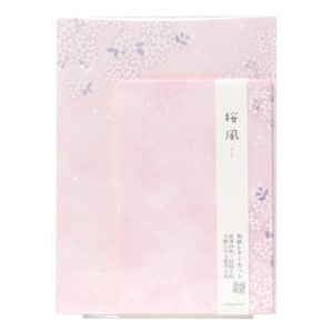以下が含まれることがあります： 淡いピンク色の便箋セットで、白と薄紫色の桜の花びらの模様が描かれています。中央には「桜風」と書かれた白い縦長の帯があり、その下にはセット内容を説明する小さな日本語の文字が印刷されています。