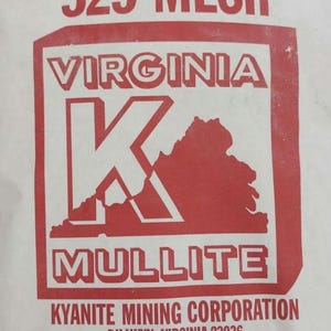 Puede incluir: Una bolsa blanca con texto y gráficos rojos. El texto dice "MULLITE 325 MESH VIRGINIA K MULLITE". Debajo, dice "KYANITE MINING CORPORATION" y "25 KG/22.68 KG". La parte inferior de la bolsa tiene una pequeña bandera estadounidense.
