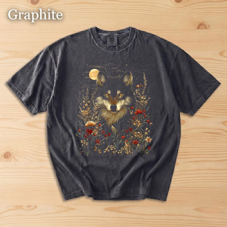 May include: Graphite-coloured t-shirt with a wolf illustration. The design features a wolf's face surrounded by flowers and a full moon. The shirt is made of a soft material and has a classic crew neck.