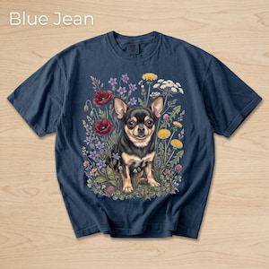 May include: Navy blue t-shirt with a colorful illustration of a Chihuahua surrounded by wildflowers. The text "Blue Jean" is at the top. The graphic features red poppies, yellow dandelions, and purple flowers.