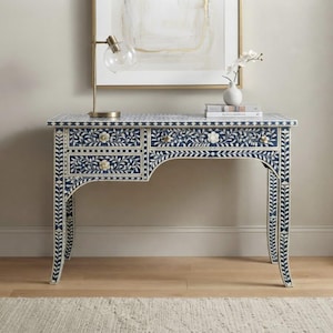 May include: A rectangular console table featuring a dark blue and white floral inlay pattern across the surface, drawers, and legs. The table has three drawers with small, round, light-colored floral-shaped knobs and curved legs.