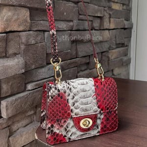 May include: A white ceramic mug with a black handle and the text "But first, coffee" in a handwritten style. The mug is on a white surface. The mug is 10 cm tall.