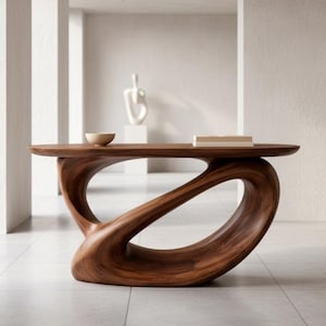 Może przedstawiać: Nowoczesny, rzeźbiarski stolik kawowy z drewna o unikalnym, płynnym designie. Stół wykonany jest z ciemnobrązowego drewna i posiada owalny blat z miską i książką. Podstawa ma ciągły, pętelkowy kształt.