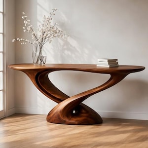 May include: A dark brown, solid wood console table with a distinctive, flowing design. The table has a sculptural base. A glass vase with white flowers and a stack of books are on the table. The table's length is approximately 180 cm.
