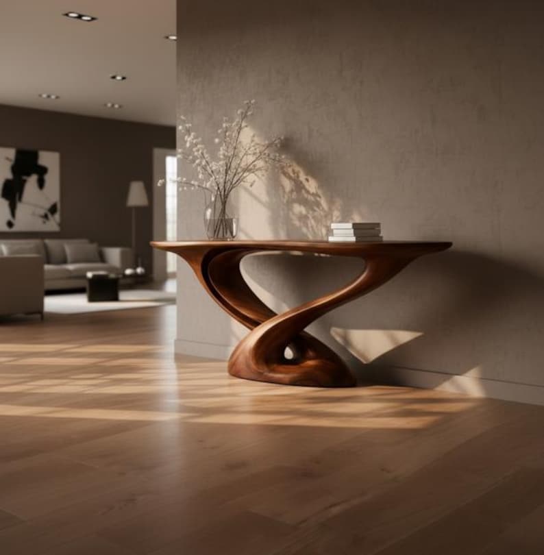 May include: A wooden console table with a distinctive, flowing design. The table is a warm brown colour and has a curved base. A vase of white flowers and a stack of books sit on top. The table is in a modern living room setting.