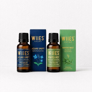 May include: Two amber glass bottles with black caps and two matching rectangular boxes. One set is blue labelled WIIES AROMA AZURE DRIFT inspired by desire blue. The other set is green labelled WIIES AROMA MINTED MIST inspired by eucalyptus.