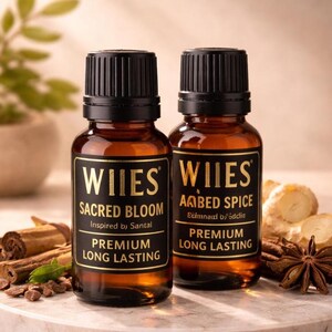 May include: Two amber glass bottles with black caps and labels. The labels read "WILES SACRED BLOOM" and "WILES AMBED SPICE". The text "PREMIUM LONG LASTING" is also visible. Cinnamon sticks and star anise are in the background.