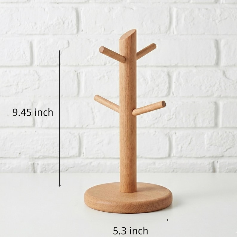 May include: A wooden mug tree with a round base and four horizontal pegs for hanging mugs. The tree is 9.45 inches tall and 5.3 inches wide. The natural wood finish complements the white brick background.