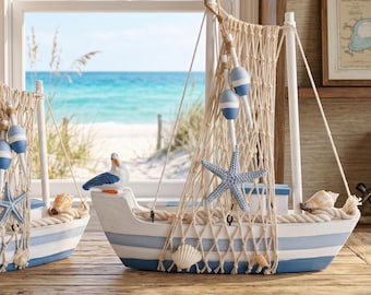 May include: Coastal-themed decorative boat with blue and white stripes, a net, and starfish accents. The boat features a seagull figurine, seashells, and blue and white buoys. The boat is displayed on a wooden surface with a beach scene in the background.