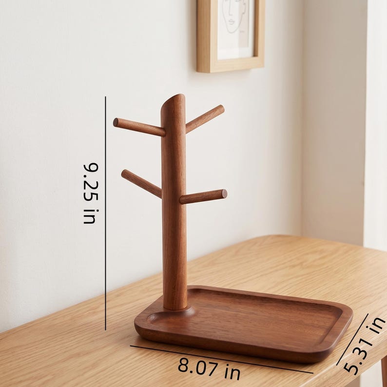 May include: A wooden mug tree with a rectangular base and a tree-like structure for hanging mugs. The mug tree is 9.25 inches tall, 8.07 inches wide, and 5.31 inches deep. The wood has a warm, brown tone.