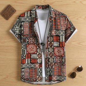 Può includere: Camicia a maniche corte con motivo geometrico nei toni del rosso, nero e crema. La camicia è indossata sopra una maglietta bianca e abbinata a una collana. Sono visibili anche occhiali da sole e un portafoglio. La camicia ha colletto e chiusura con bottoni.