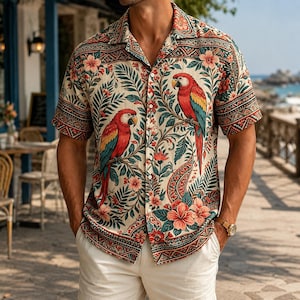 Peut inclure: Une chemise à manches courtes boutonnée sur fond crème avec un imprimé vif de perroquets rouges et jaunes perchés sur des branches, entourés de feuilles tropicales vertes et de fleurs d'hibiscus roses, avec une bordure à motifs.
