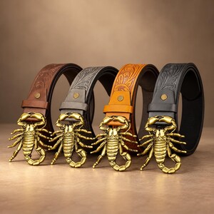 May include: Four belts arranged in a row, each featuring a gold-toned metal scorpion buckle. The leather straps come in brown, grey, tan, and black, all displaying an embossed floral pattern along the length of the belt and a single metal stud.