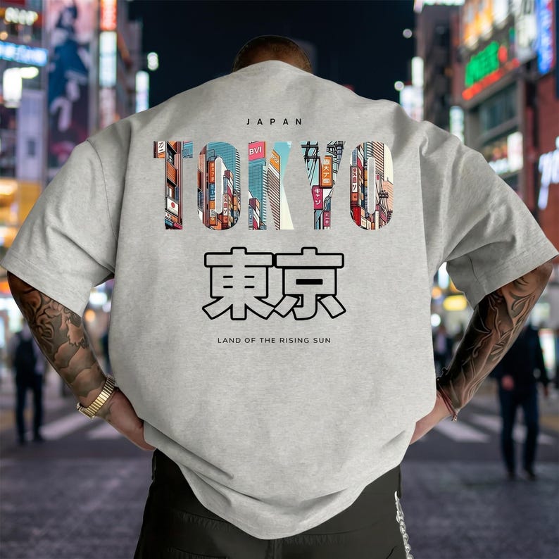 May include: A light gray t-shirt with the word "TOKYO" in colorful block letters, with the Japanese characters for Tokyo below. The word "JAPAN" is above "TOKYO" and "LAND OF THE RISING SUN" is below.