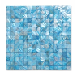 Op de afbeelding: Een vierkant mozaïektegelvel bestaande uit kleine, individuele vierkante stukjes iriserende parelmoerschelp. De tegels hebben een verloop van lichtblauwe, turquoise en witte tinten met een natuurlijke, reflecterende en parelmoerachtige afwerking.