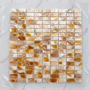 May include: A rectangular mosaic tile sheet composed of small, individual rectangular pieces of iridescent mother-of-pearl shell. The tiles feature a natural color palette of creamy white, beige, and warm golden-brown tones with a glossy finish.