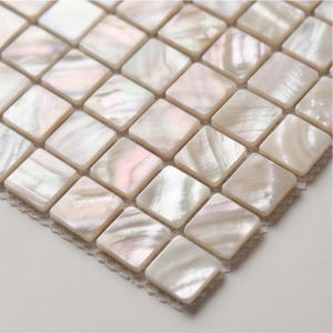 May include: Close-up of a mosaic tile sheet featuring numerous square tiles with rounded corners. The tiles have a pearlescent, iridescent finish with subtle pink and white hues. The tiles are arranged in a grid pattern.