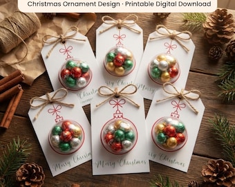 Può includere: Sei etichette regalo rettangolari bianche con un disegno a linee rosse di una pallina di Natale. Ogni etichetta ha una bolla di plastica trasparente riempita con piccoli cioccolatini avvolti in carta stagnola rossa, verde, oro e argento.