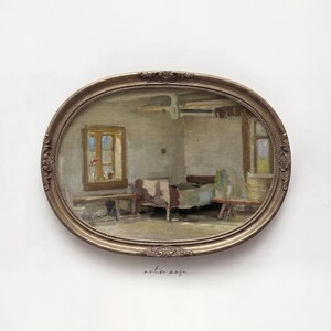 May include: An oval-shaped, antique-style painting in a gold frame. The artwork depicts a rustic interior scene with a bed, window, and table. The color palette is muted, with earthy tones and soft lighting, creating a vintage aesthetic.
